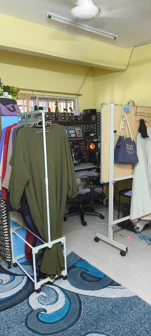 Ruang home studio kecil di rumah dengan rak baju sebagai pembahagi dan meja kerja di sudut bilik